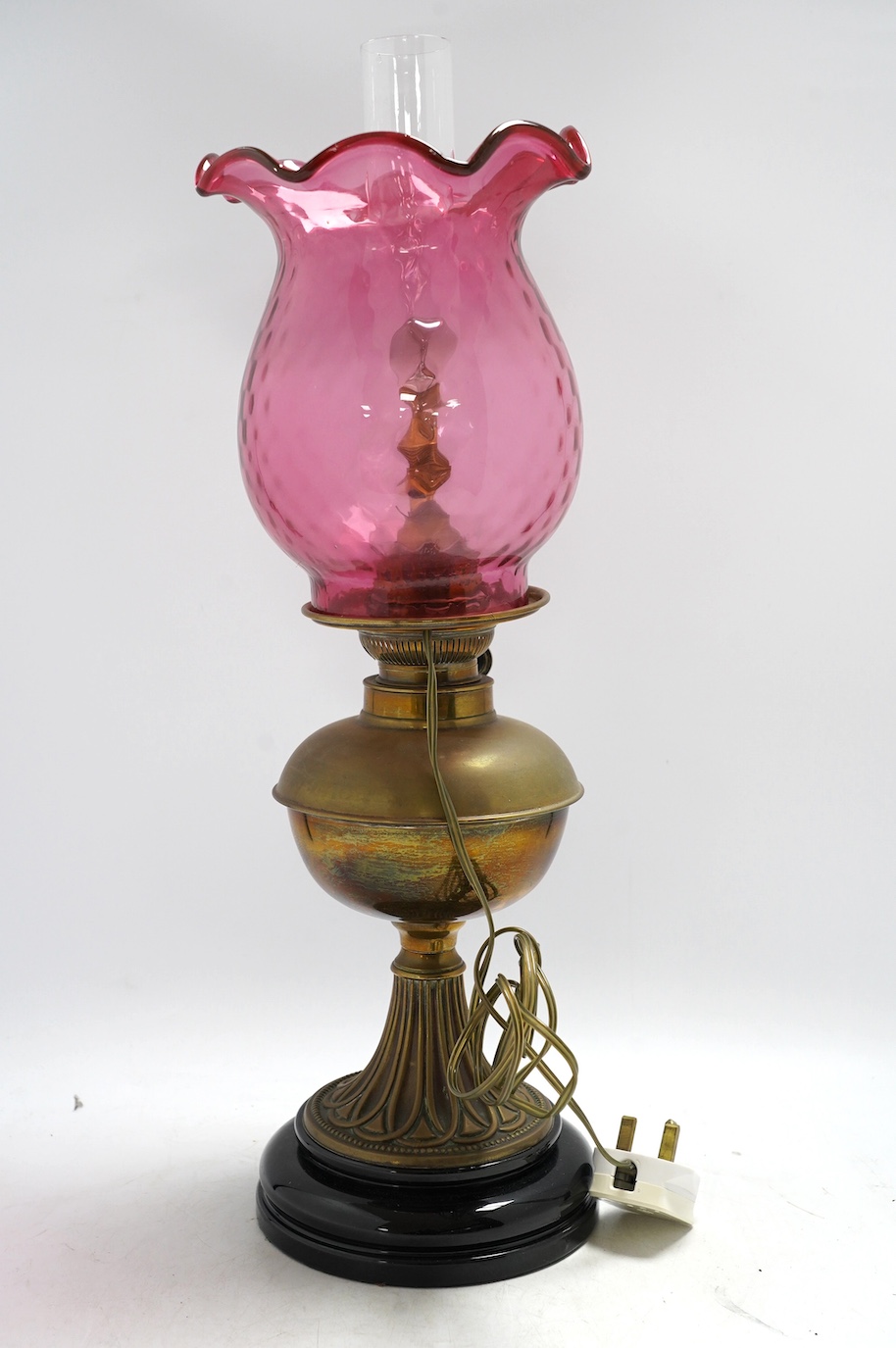 A Victorian brass oil lamp with cranberry glass shade. Condition - fair